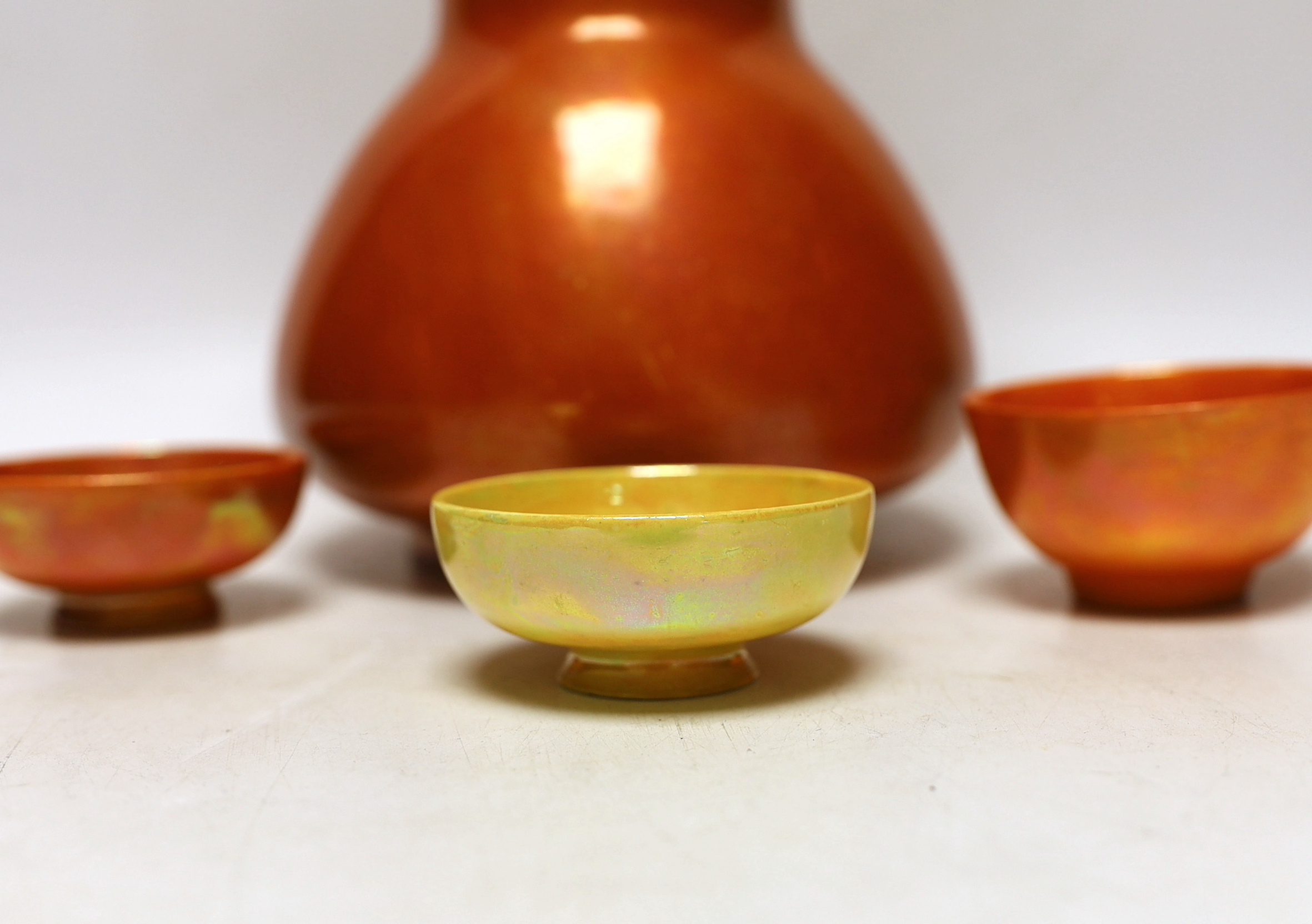 A Ruskin orange glazed vase (a.f) and three similar small bowls by Ruskin and Doulton, vase 23.5cm